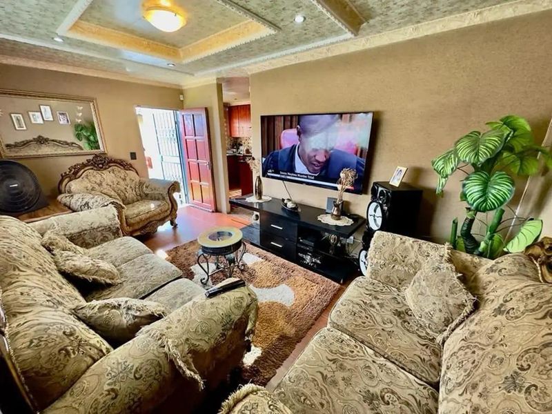 A living room featuring a decorative tray ceiling with recessed lighting and laminate flooring, providing a comfortable space for relaxation.