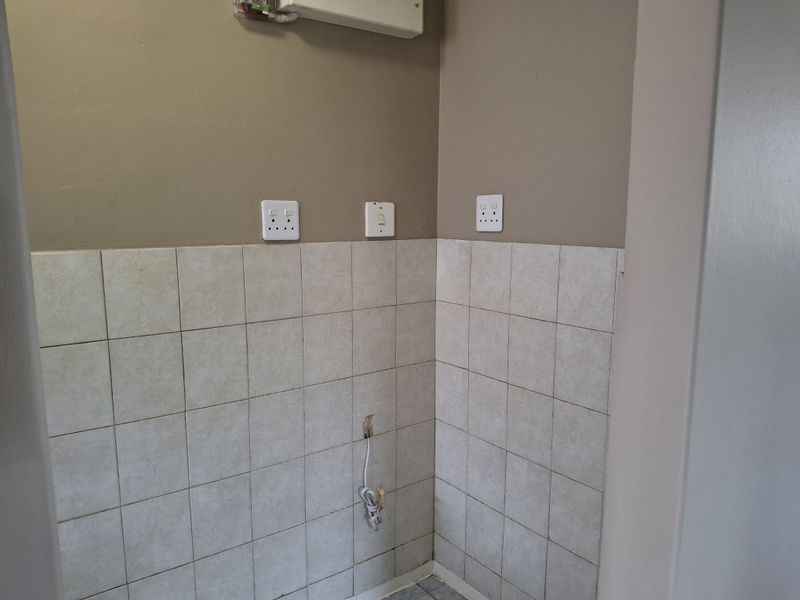 A functional laundry or utility area featuring tiled splashbacks and electrical points, currently awaiting appliance installation.