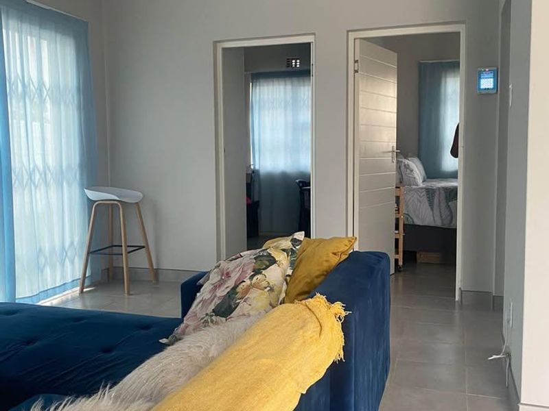 A bright living area featuring tiled floors, a tongue and groove ceiling with recessed lighting, and access to adjacent rooms.