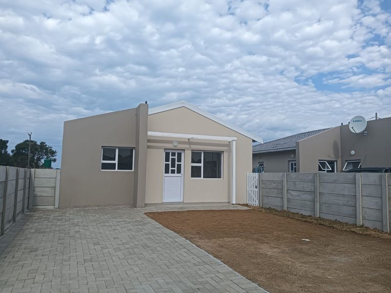 Front view of a modern single-story apartment featuring a paved driveway, precast boundary walls, and a clean exterior facade.