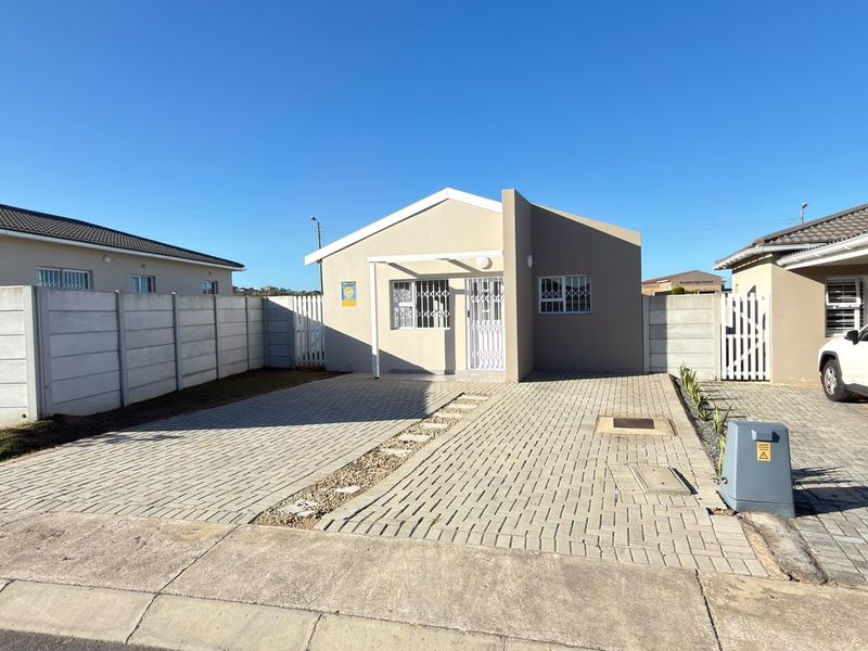 Front elevation of a modern apartment featuring a paved driveway, secure gated entrance, and perimeter boundary walls.