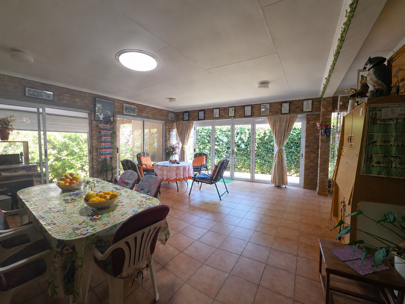 Spacious living area featuring exposed brick walls, tiled flooring, and multiple sliding glass doors providing ample natural light and garden access.