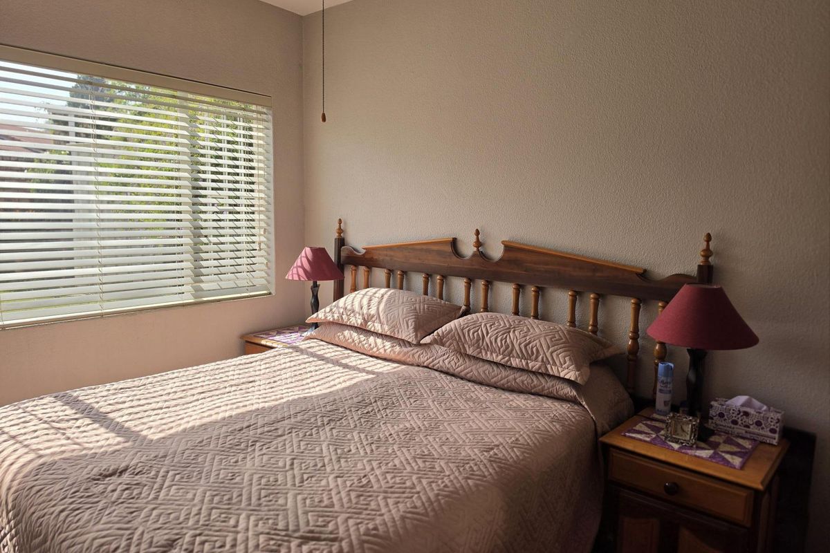 A bedroom featuring textured walls and venetian blinds, providing natural light and a neutral foundation for potential updates.