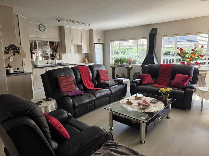Open-plan living area featuring a kitchen with built-in cabinetry and a lounge space with a modern fireplace and laminate flooring.