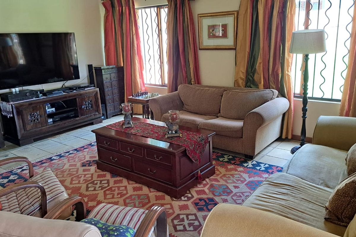 A comfortable living room featuring tiled flooring and windows fitted with security bars, providing a functional and lived-in space.