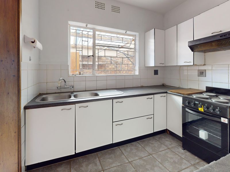 A functional kitchen featuring white cabinetry, laminate countertops, a double sink, and a freestanding oven with an extractor fan.