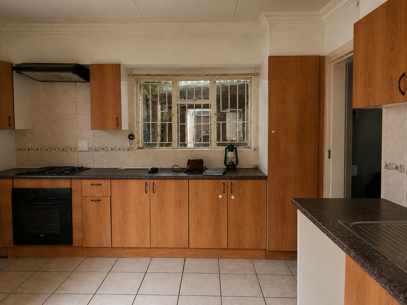 A functional kitchen featuring wood-look cabinetry, built-in oven, gas hob, extractor fan, and tiled flooring, offering a practical layout with ample storage space.