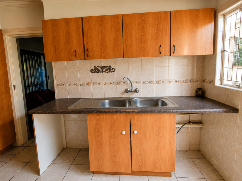 A functional scullery area featuring laminate cabinetry, a double bowl stainless steel sink, and tiled finishes, providing a practical space for kitchen prep and cleanup.