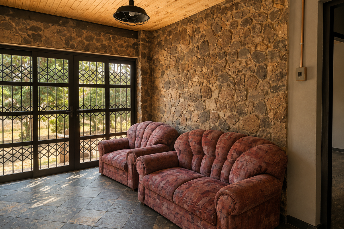 A living area featuring a rustic stone feature wall, timber ceiling, and large sliding glass doors with security gates leading to the exterior.
