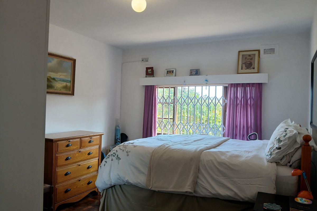A bedroom featuring parquet flooring, a security gate on the window, and a ceiling light fixture.