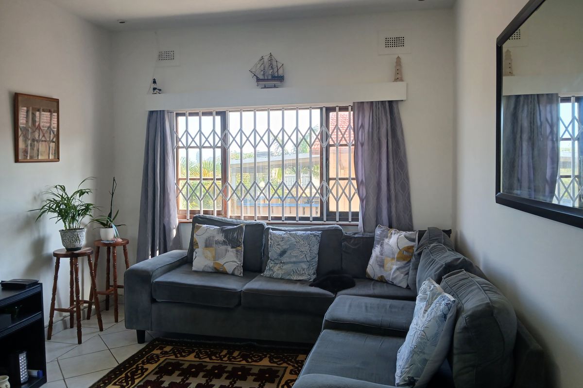 A comfortable living room featuring tiled flooring, recessed lighting, and a window fitted with a security gate.