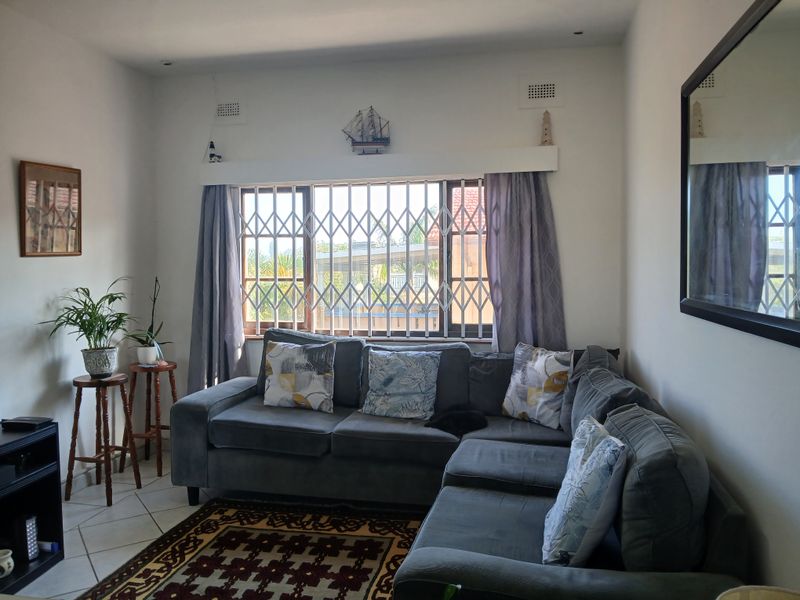 A comfortable living room featuring tiled flooring, recessed lighting, and a window fitted with a security gate.