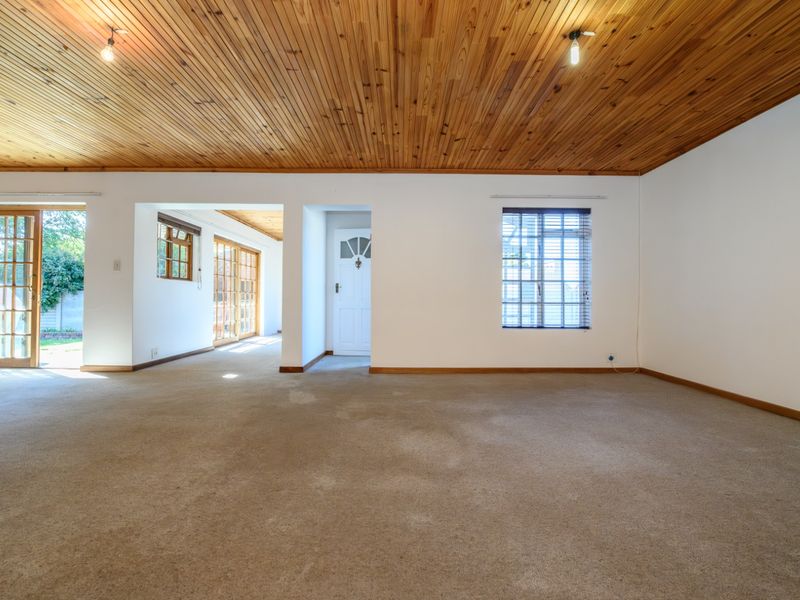 Spacious living area featuring a timber tongue and groove ceiling, carpeted flooring, and direct access to an outdoor patio through sliding glass doors.