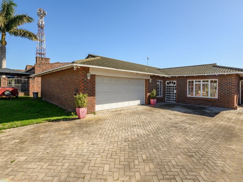 Front view of a brick house featuring a paved driveway, a single garage, and a secure entrance.