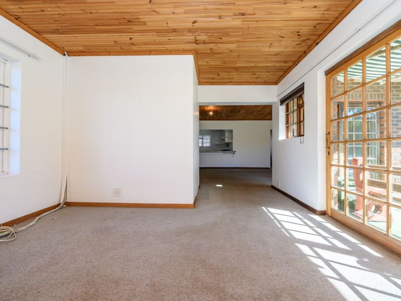 Spacious living area featuring a timber ceiling, carpeted flooring, and large sliding glass doors providing access to the outdoor patio area.