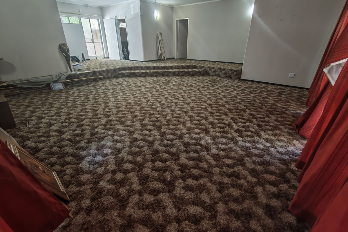 Spacious living area featuring a raised platform and wall-to-wall carpeting, offering a versatile layout ready for modernization.