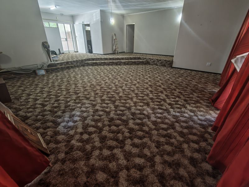 Spacious living area featuring a raised platform and wall-to-wall carpeting, offering a versatile layout ready for modernization.