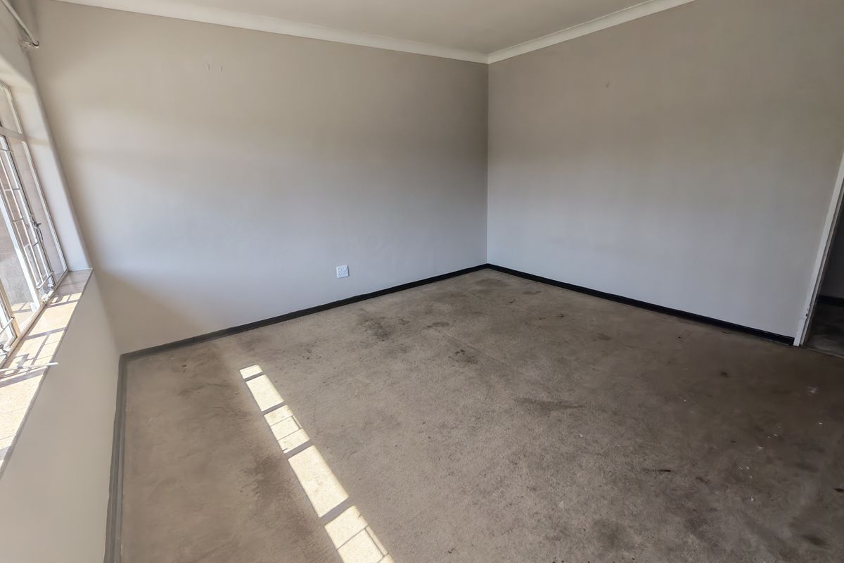 An empty bedroom featuring neutral walls, coving, and a window, currently requiring flooring replacement and general cosmetic refurbishment.
