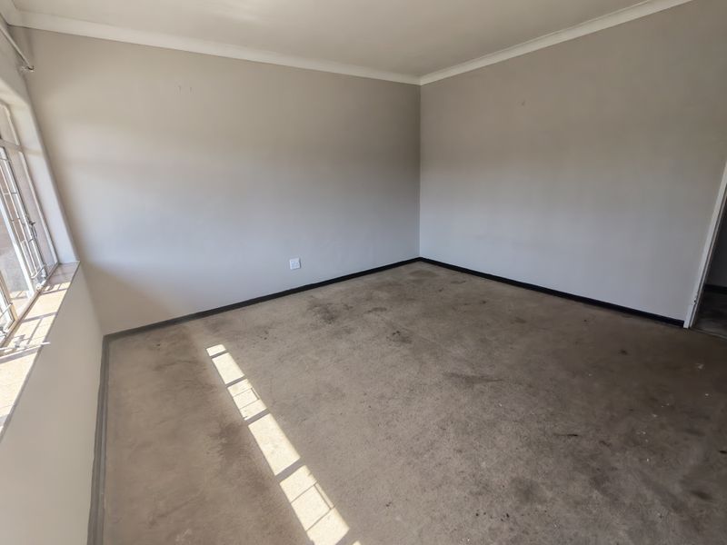 An empty bedroom featuring neutral walls, coving, and a window, currently requiring flooring replacement and general cosmetic refurbishment.