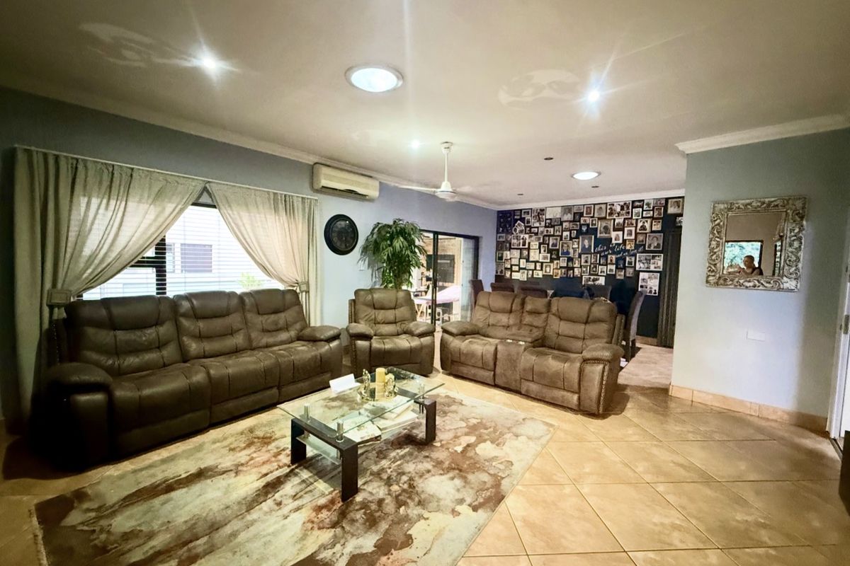 Spacious living room featuring tiled flooring, split-system air conditioning, ceiling fan, and natural light provided by skylights and large windows.