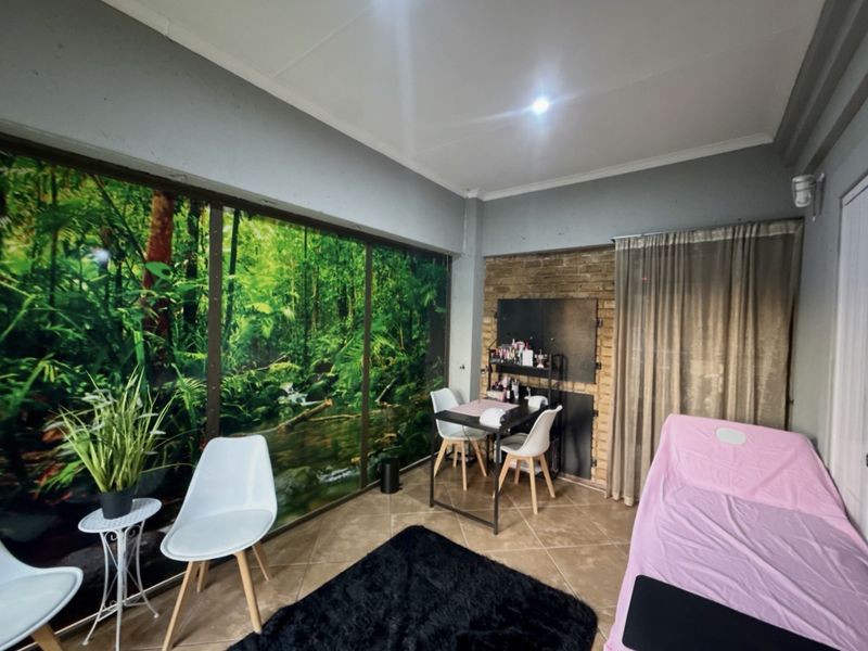 A bedroom space featuring tiled flooring, an exposed brick accent wall, and a large sliding glass door with a forest-themed mural.
