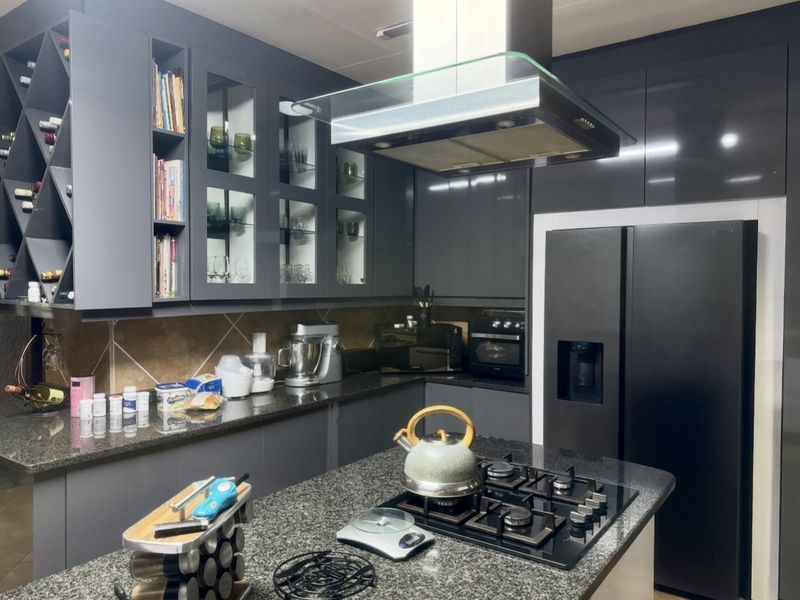 Modern kitchen featuring dark grey cabinetry, granite countertops, a central island with a gas hob, and integrated extractor fan.
