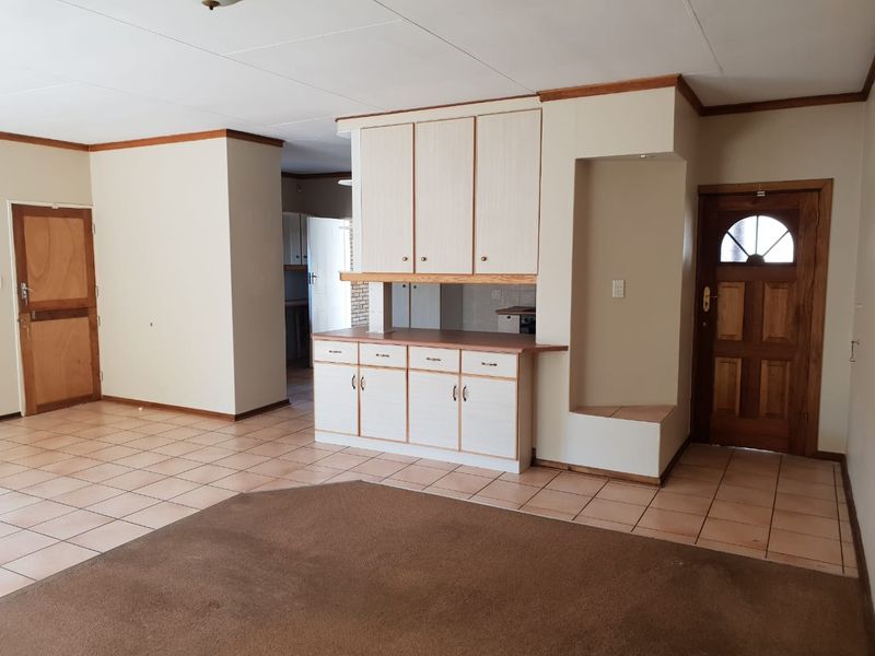 Open plan living area featuring tiled flooring and built-in cabinetry, offering a versatile space ready for renovation and modern updates.