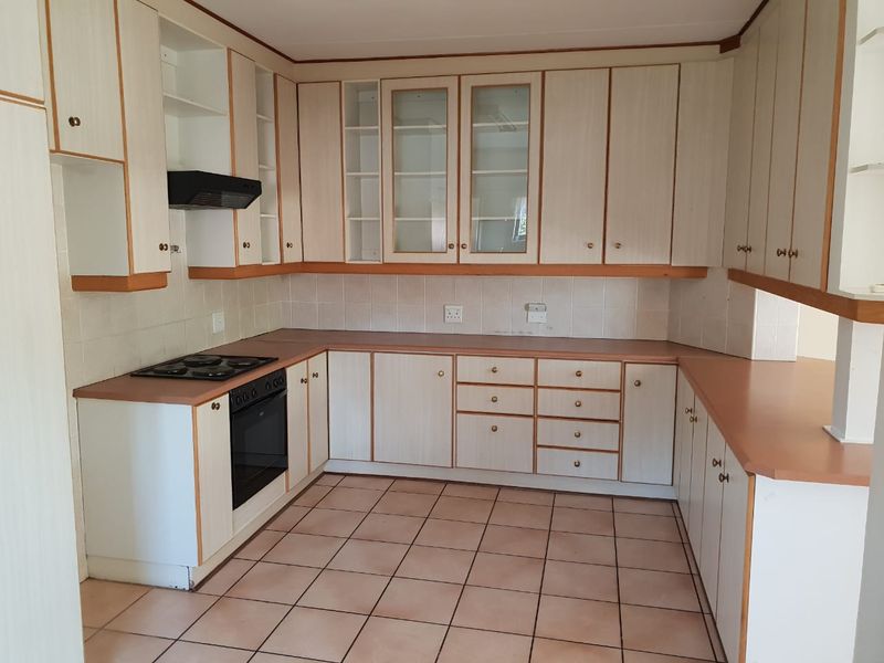 A functional kitchen featuring built-in cabinetry, laminate countertops, a built-in oven with hob, and ceramic tile flooring.