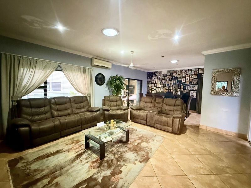 Spacious living room featuring tiled flooring, split-system air conditioning, ceiling fan, and natural light provided by skylights and large windows.