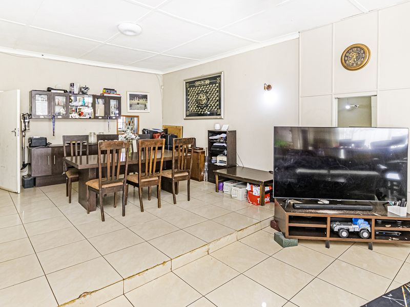 Open-plan living and dining area featuring tiled flooring, a raised platform section, and a decorative stone feature wall.