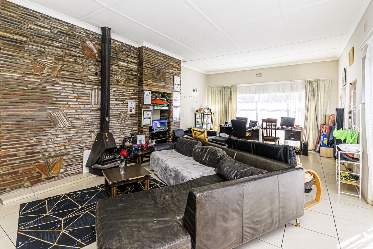 Spacious living room featuring a prominent stone feature wall with a built-in fireplace and neutral tiled flooring throughout.