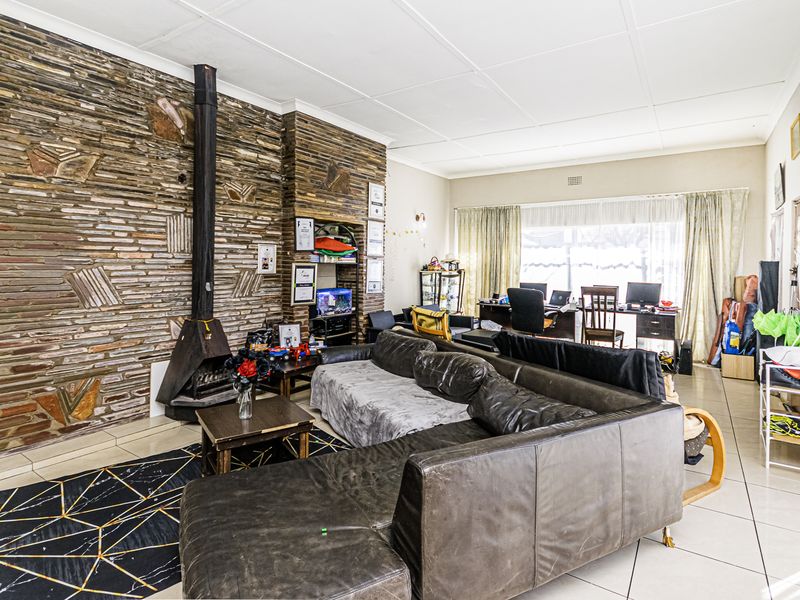 Spacious living room featuring a prominent stone feature wall with a built-in fireplace and neutral tiled flooring throughout.
