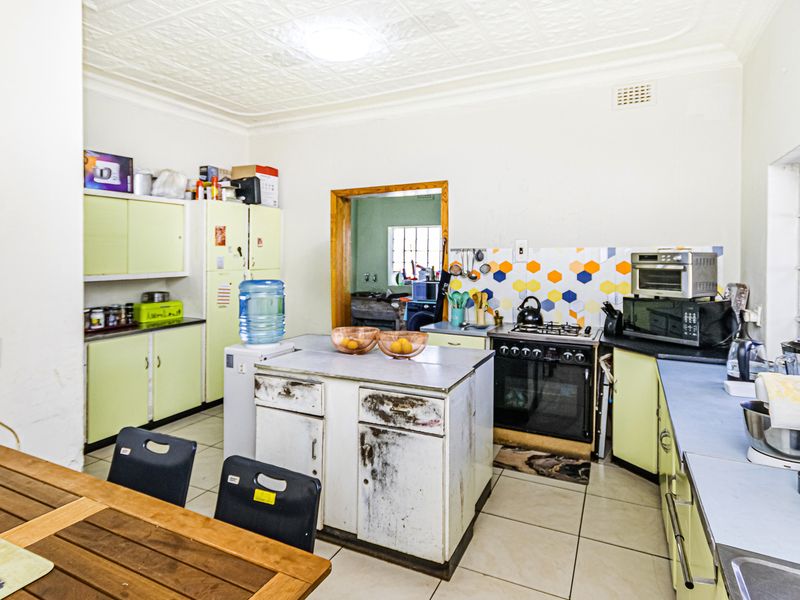A functional kitchen featuring built-in cabinetry, a gas stove, and tiled flooring, with potential for cosmetic updates to modernize the space.