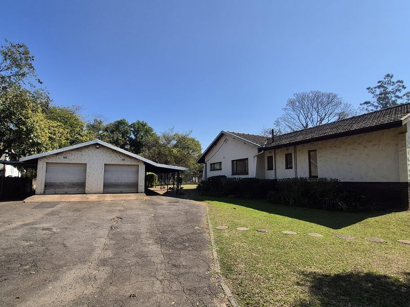 Front view of a single-story house featuring a double garage, an asphalt driveway, and a well-maintained lawn area.
