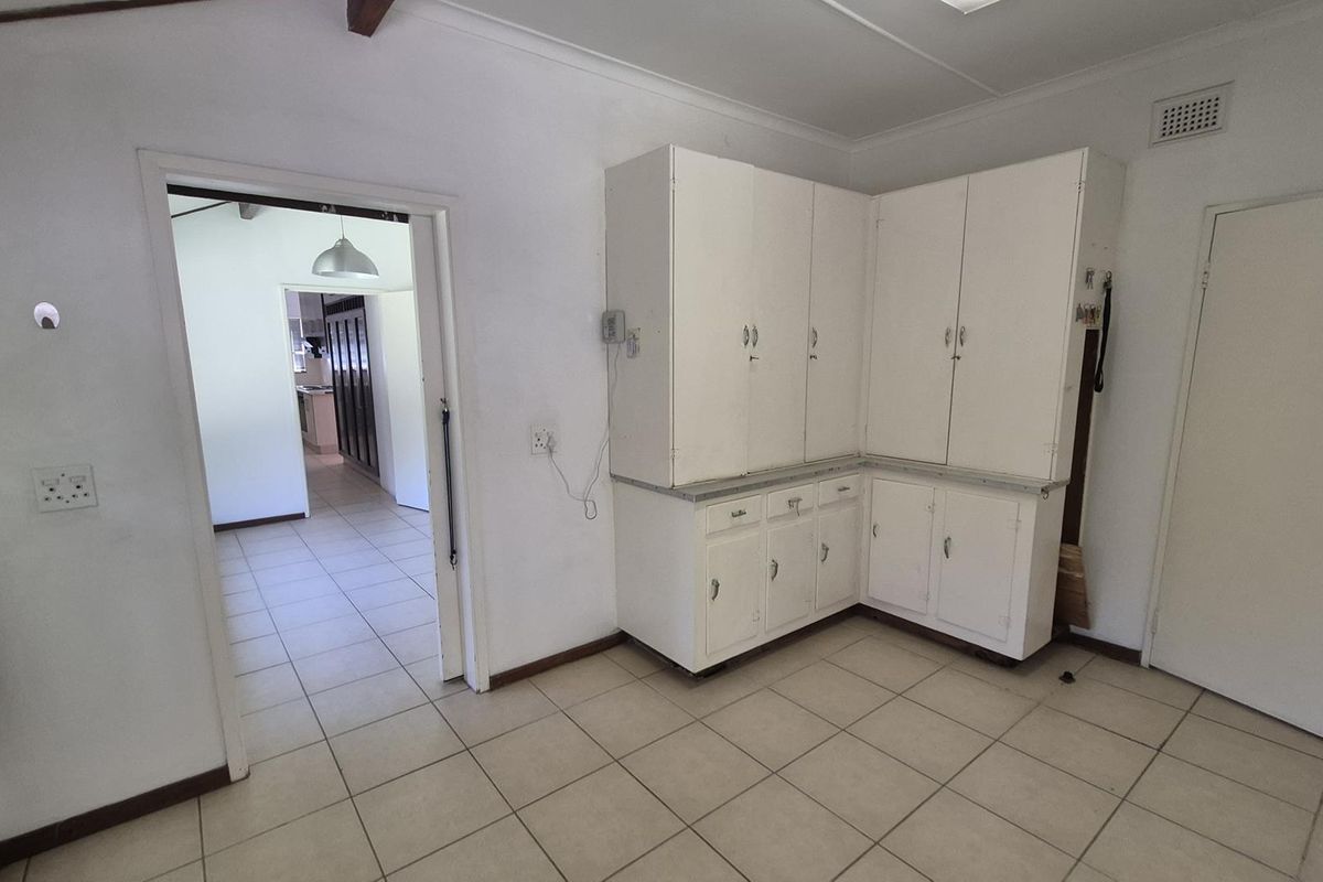 A functional kitchen area featuring built-in white cabinetry and tiled flooring, offering a blank canvas for potential modern renovation and design updates.
