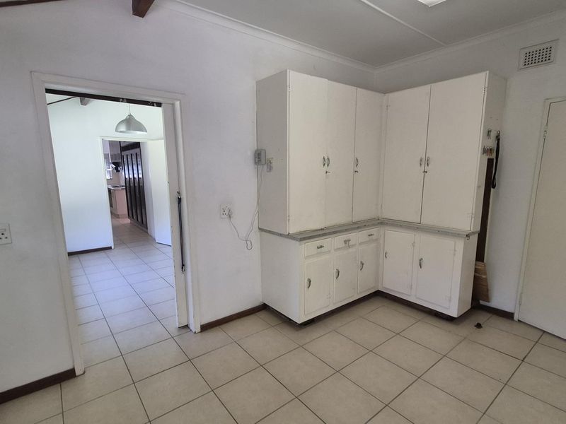 A functional kitchen area featuring built-in white cabinetry and tiled flooring, offering a blank canvas for potential modern renovation and design updates.