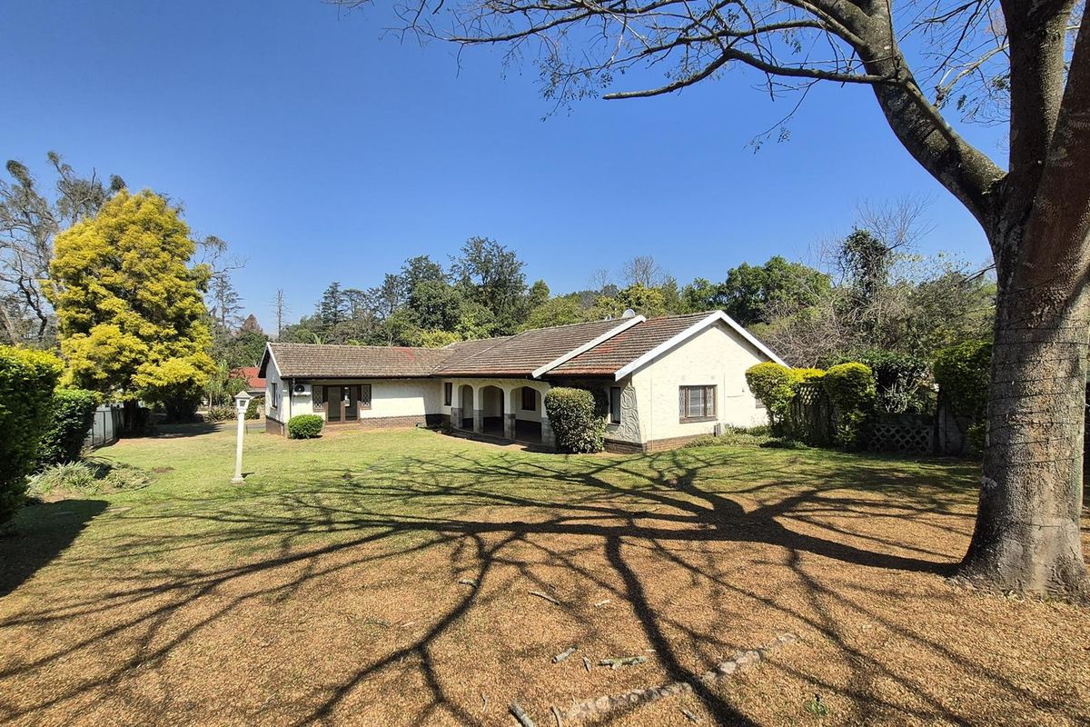 A view of the rear elevation of the house featuring a covered patio area and a spacious, established garden.