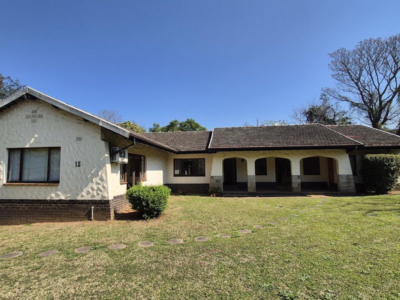 A single-story residential home featuring a textured stucco facade, brick base, tiled roof, and a covered arched porch entrance.