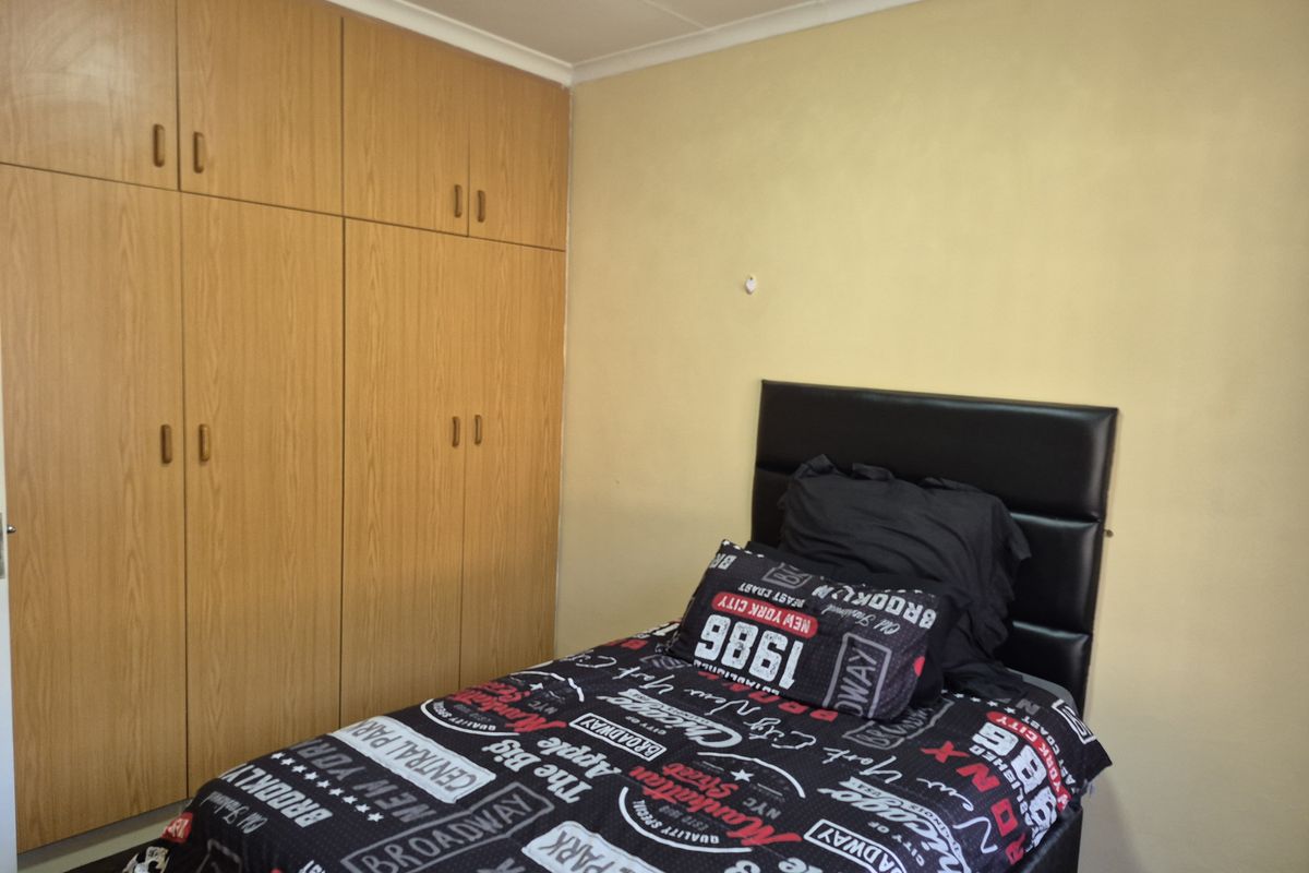 A bedroom featuring built-in wooden cupboards and neutral wall finishes, offering functional storage space.
