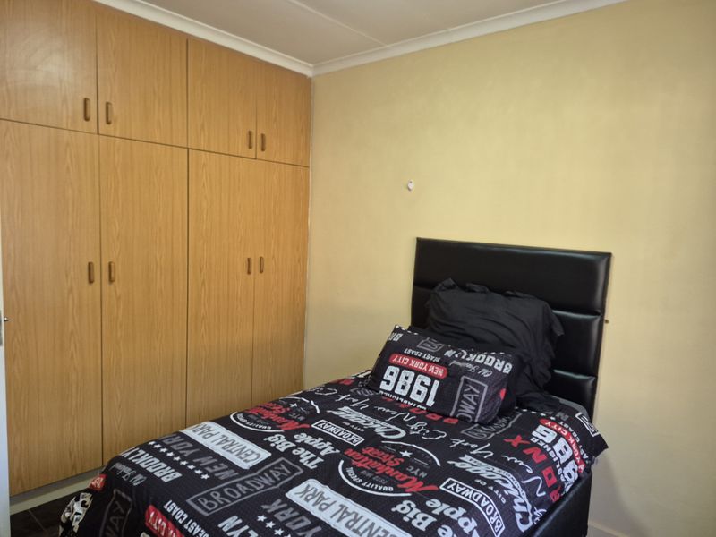 A bedroom featuring built-in wooden cupboards and neutral wall finishes, offering functional storage space.