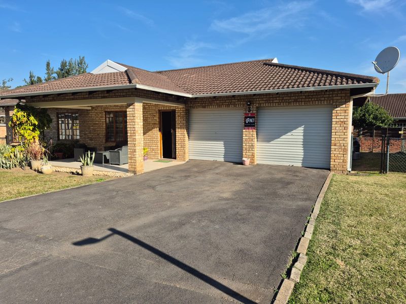 Front view of a brick townhouse featuring a double garage, asphalt driveway, and a covered patio area.
