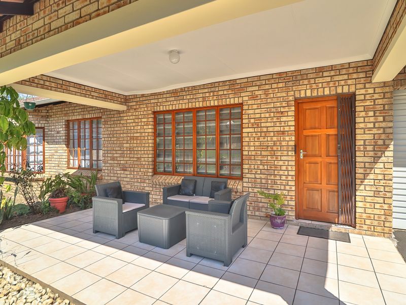 A covered patio area featuring exposed brick walls, tiled flooring, and timber-framed windows, providing a functional outdoor living space.