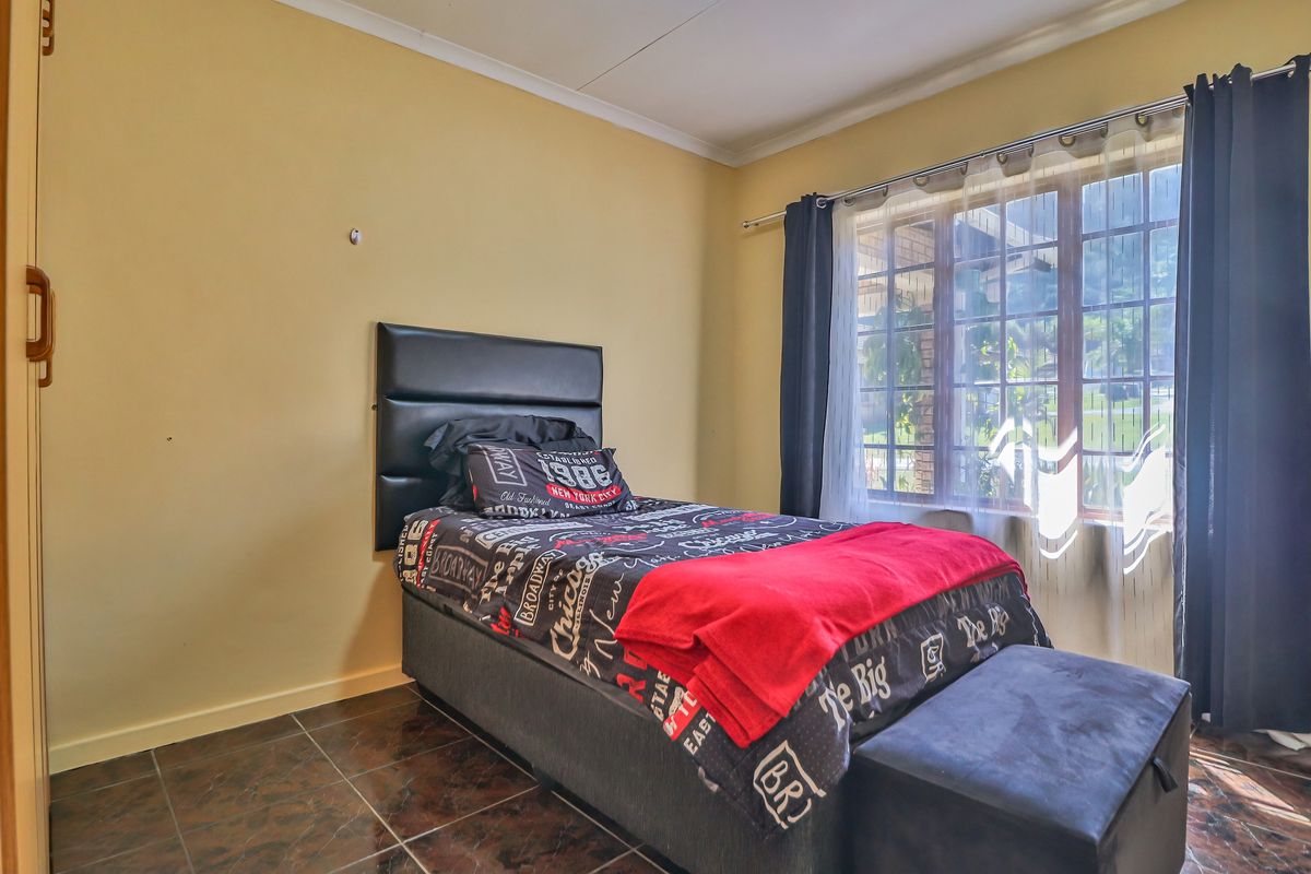 A bedroom featuring tiled flooring, a built-in cupboard, and natural light through a window with curtain rods.
