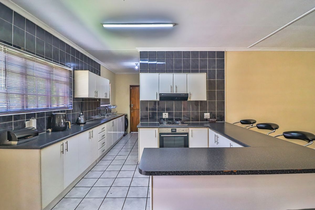 Functional kitchen featuring dark tiled backsplash, ample cabinetry, built-in oven with gas hob, and a breakfast bar counter.