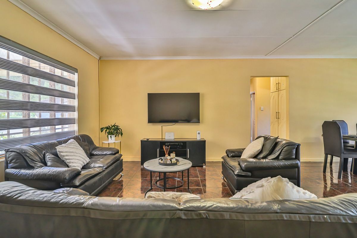 A comfortable living room featuring tiled flooring, neutral wall tones, and access to adjacent storage or hallway areas.