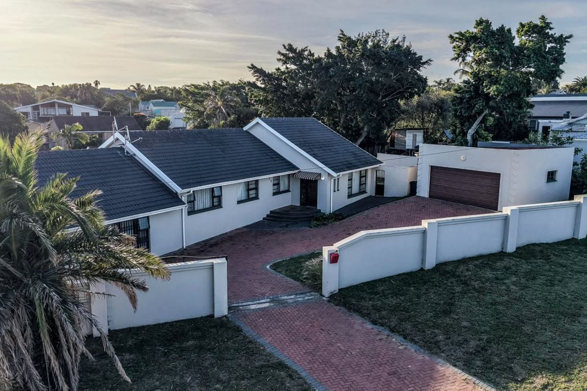 Aerial view of a well-maintained single-story house featuring a tiled roof, brick-paved driveway, and secure perimeter walling.