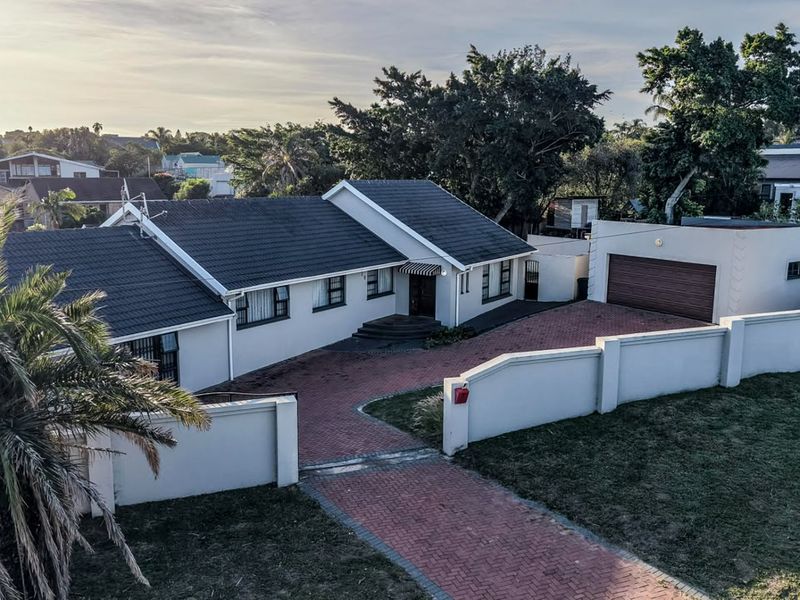 Aerial view of a well-maintained single-story house featuring a tiled roof, brick-paved driveway, and secure perimeter walling.