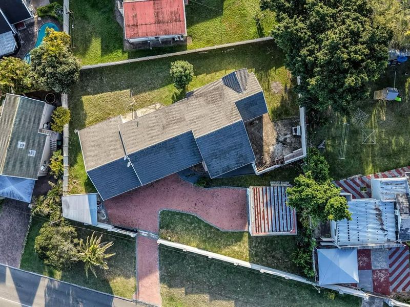 Aerial view of the residential property showing the main house, paved driveway, surrounding garden, and boundary walls.