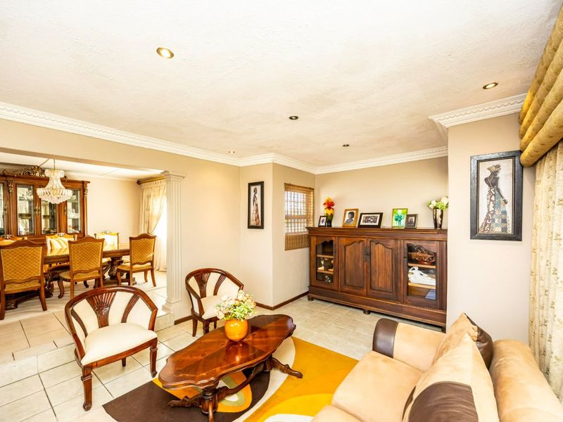 Spacious open-plan living and dining area featuring tiled flooring, recessed lighting, and elegant crown molding throughout the connected living spaces.