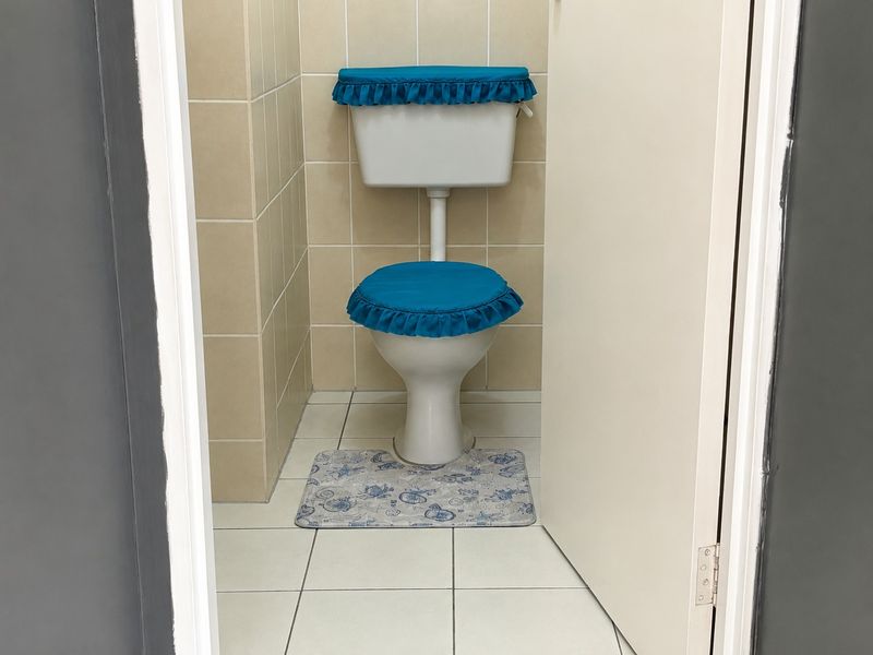 A compact bathroom featuring a standard ceramic toilet with neutral wall and floor tiling.